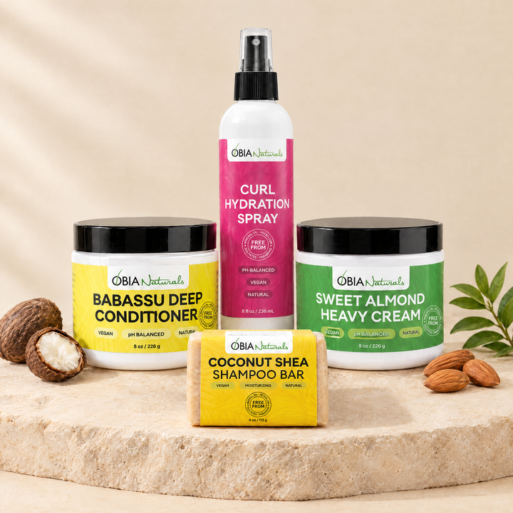 OBIA Naturals Low Porosity Hair Bundle with Coconut Shea Shampoo Bar — shampoo bar, Babassu Deep Conditioner, Curl Hydration Spray and Sweet Almond Heavy Cream arranged on a stone plinth