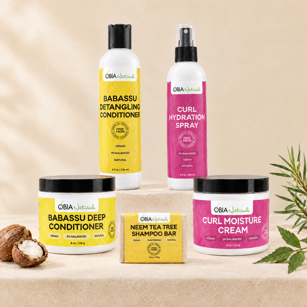 OBIA Naturals Protein-Free, Coconut-Oil-Free Hair Bundle with Curl Moisture Cream — Neem Tea Tree Shampoo Bar, Babassu Deep Conditioner, Babassu Detangling Conditioner, Curl Hydration Spray and Curl Moisture Cream arranged on a stone plinth