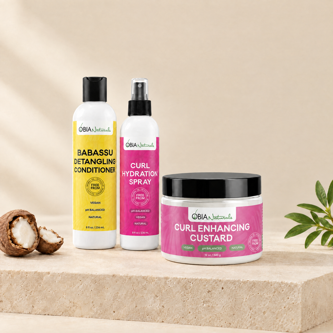 OBIA Naturals Defined Wash N Go Bundle — Babassu Detangling Conditioner, Curl Hydration Spray and Curl Enhancing Custard arranged on a stone plinth